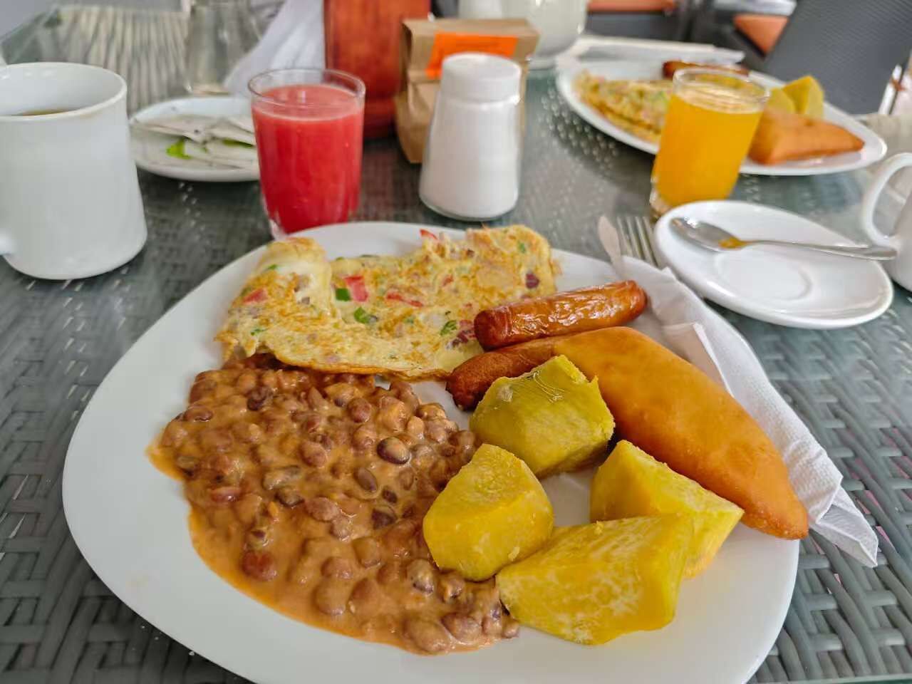 A breakfast plate with beans, eggs, sausage, and plantains.