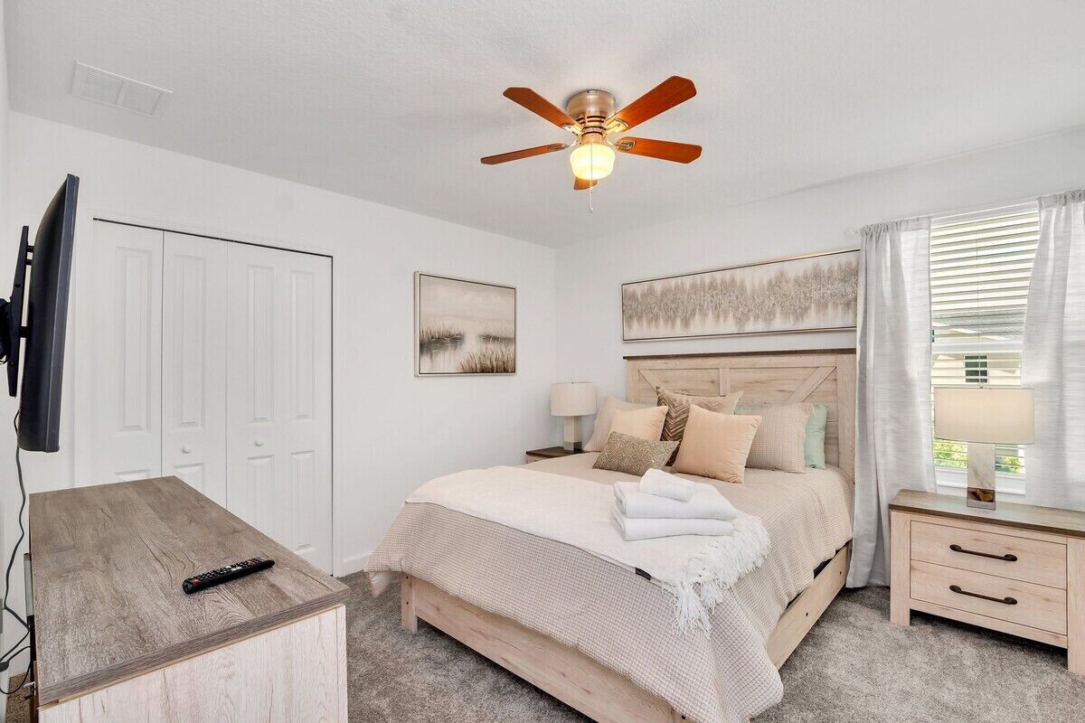 A bedroom with a bed, bedside tables, a ceiling fan, and a TV.