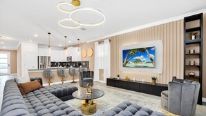 A modern living room with a large grey sectional sofa, a round coffee table, and a TV mounted on the wall. - Last Minute Disney! Private Pool, Hot Tub, Game Room & Themed Bedrooms. Book Now! #118573 (Orlando)