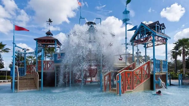 A water park with a central water feature, play structures, and palm trees. - Last Minute Disney! Private Pool, Hot Tub, Game Room & Themed Bedrooms. Book Now! #118573 (Orlando)