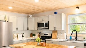 Uma cozinha moderna com ilha de madeira, banquetas, eletrodomésticos de aço inoxidável e uma janela com vista.