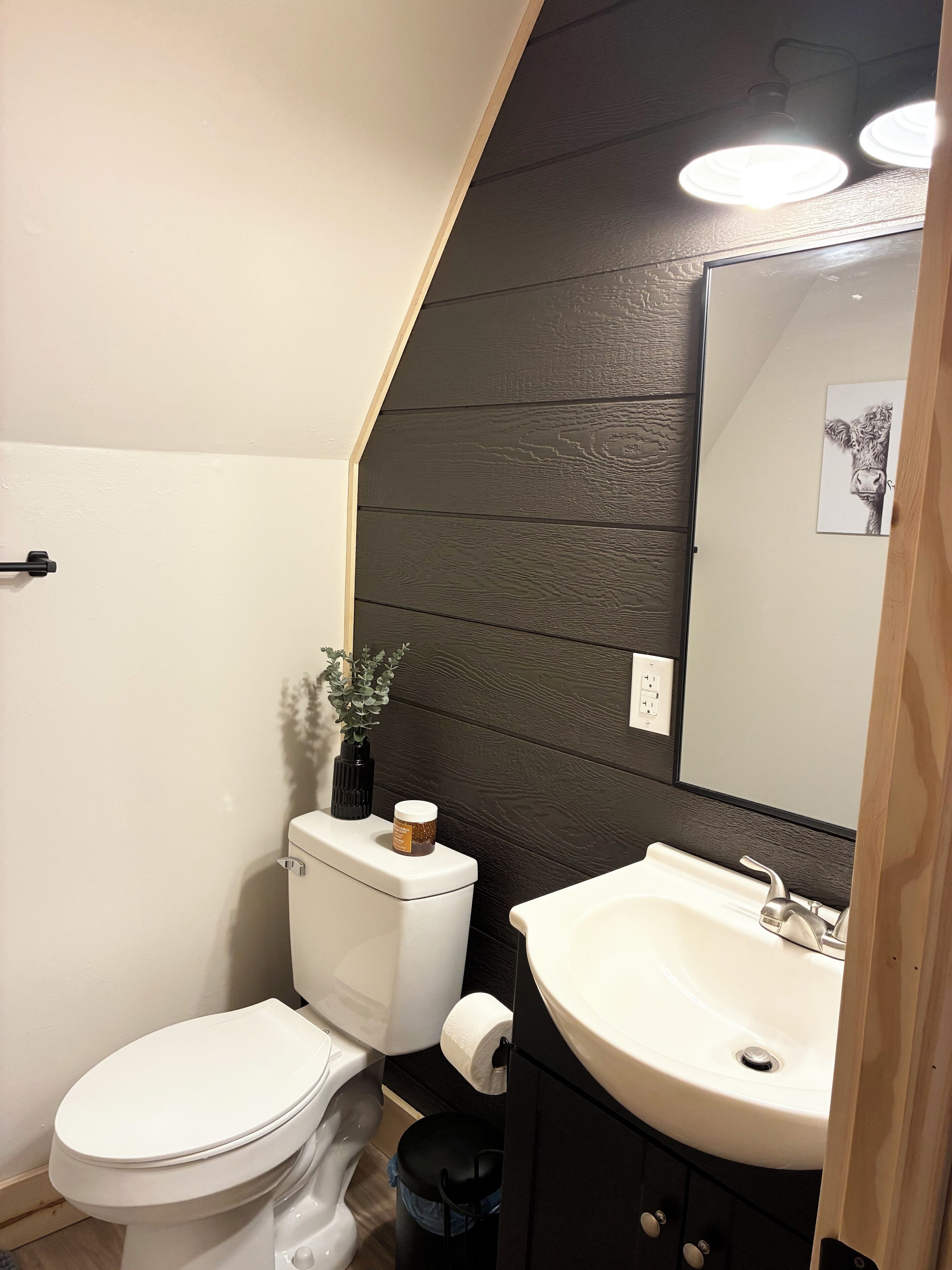 Ein Badezimmer mit Toilette, Waschbecken, Spiegel und einer Wandleuchte.