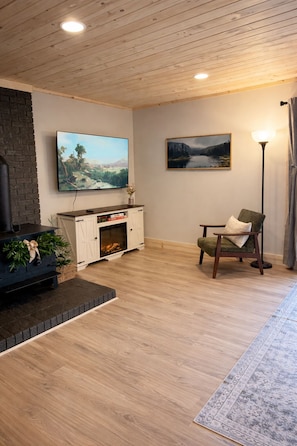 A living room with a fireplace, a television, a sofa, a chair, and a rug.