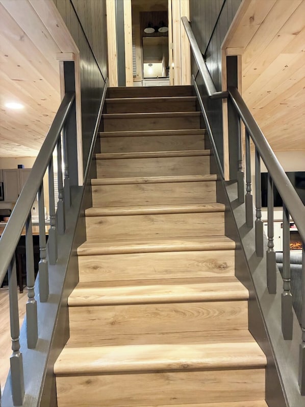 A wooden staircase with metal railings leading to a kitchen area.