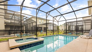Une piscine dotée d’une enceinte en verre, entourée d’un patio aménagé avec des chaises longues.