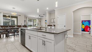 Une cuisine moderne avec des armoires blanches, un grand îlot central et des luminaires suspendus.