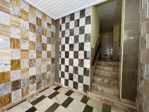 Un couloir doté d’un sol à motifs à carreaux et d’un escalier dont les marches sont recouvertes de marbre.
