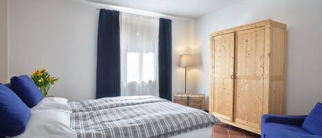 Une chambre à coucher avec un lit, une armoire, un canapé et une fenêtre avec des rideaux.