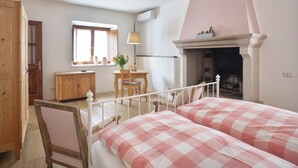Una camera da letto con camino, una scrivania in legno, una sedia e un letto con copriletto a quadretti.