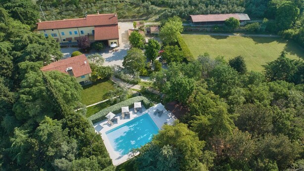 Vista aerea di una proprietà con piscina, diversi edifici e vegetazione circostante.