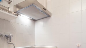 Una cucina moderna con mobili bianchi, un lavello in acciaio inossidabile, forno integrato e cappa aspirante.