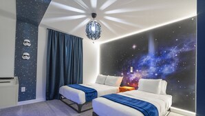 Ein Schlafzimmer mit zwei Betten, einer Wandmalerei mit Sternen und einer Deckenleuchte im Weltall-Design.