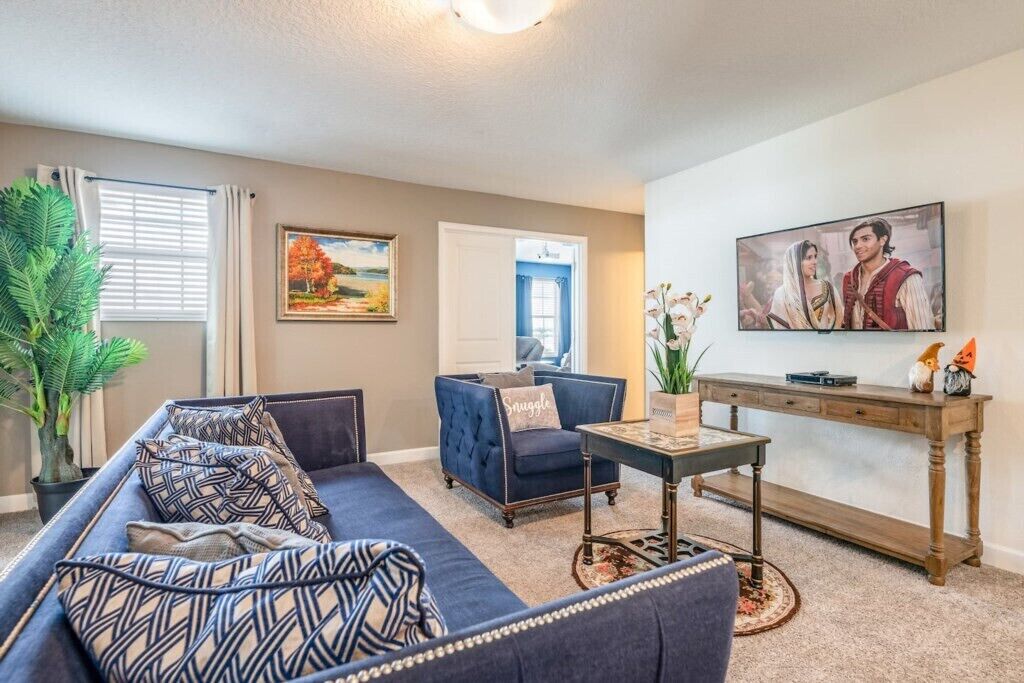 A living room with a blue sofa, a coffee table, a painting, and a console table with decorative items.