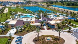 Vista aérea de un complejo turístico con varias piscinas, un puerto deportivo y un amplio estacionamiento.