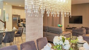 Un comedor moderno con una mesa de vidrio dispuesta para una comida, una lámpara decorativa y un conjunto de asientos cómodo.