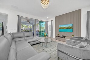 Ein modernes Wohnzimmer mit einer Eckcouch, einem Glastisch und einem flachbildfernseher an der Wand.