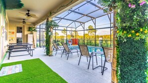 Un espacio exterior cubierto con piscina, asientos y cerramiento de vidrio.