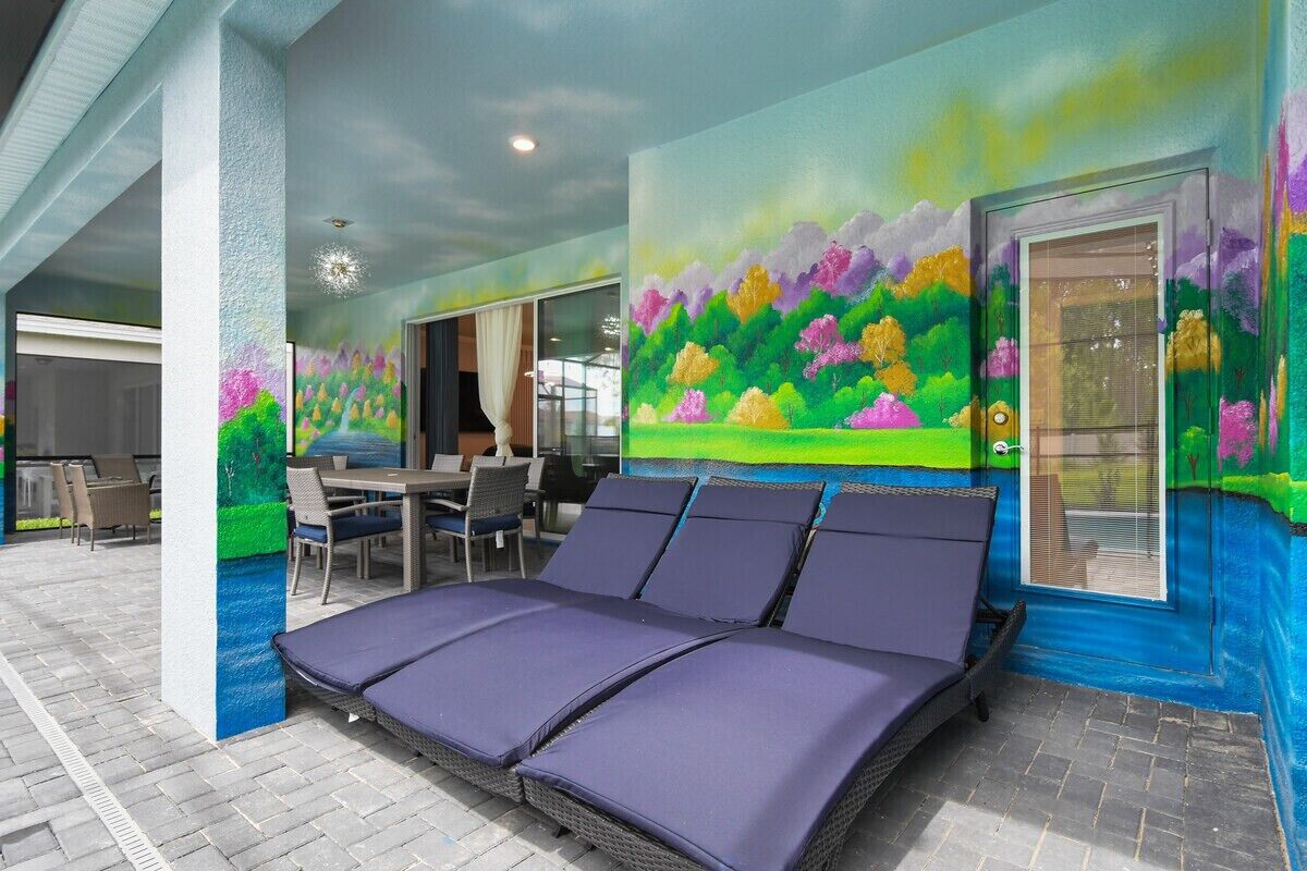 A room with a large bed, a dining area, and a mural on the wall.