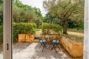 An outdoor patio with a table and chairs, surrounded by greenery and trees. - Gite 'Gite Du Petit Bois' with Shared Pool, Wi-Fi, and Air Conditioning (Villedieu)