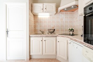 Uma cozinha com armários brancos, forno embutido e painel de azulejos.
