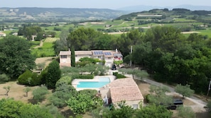 A villa with a swimming pool, surrounded by lush greenery and a scenic countryside view. - Gite 'Gite Du Petit Bois' with Shared Pool, Wi-Fi, and Air Conditioning (Villedieu)