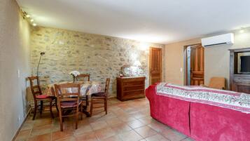 A dining area with a stone wall, wooden furniture, and a red sofa.