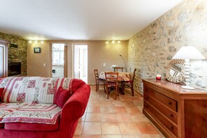 A cozy living room with a red sofa, a wooden dresser, and a dining area with a table and chairs. - Apartment 'Gite Du Petit Bois - Bignone' with Shared Pool, Wi-Fi and Air Conditioning (Villedieu)