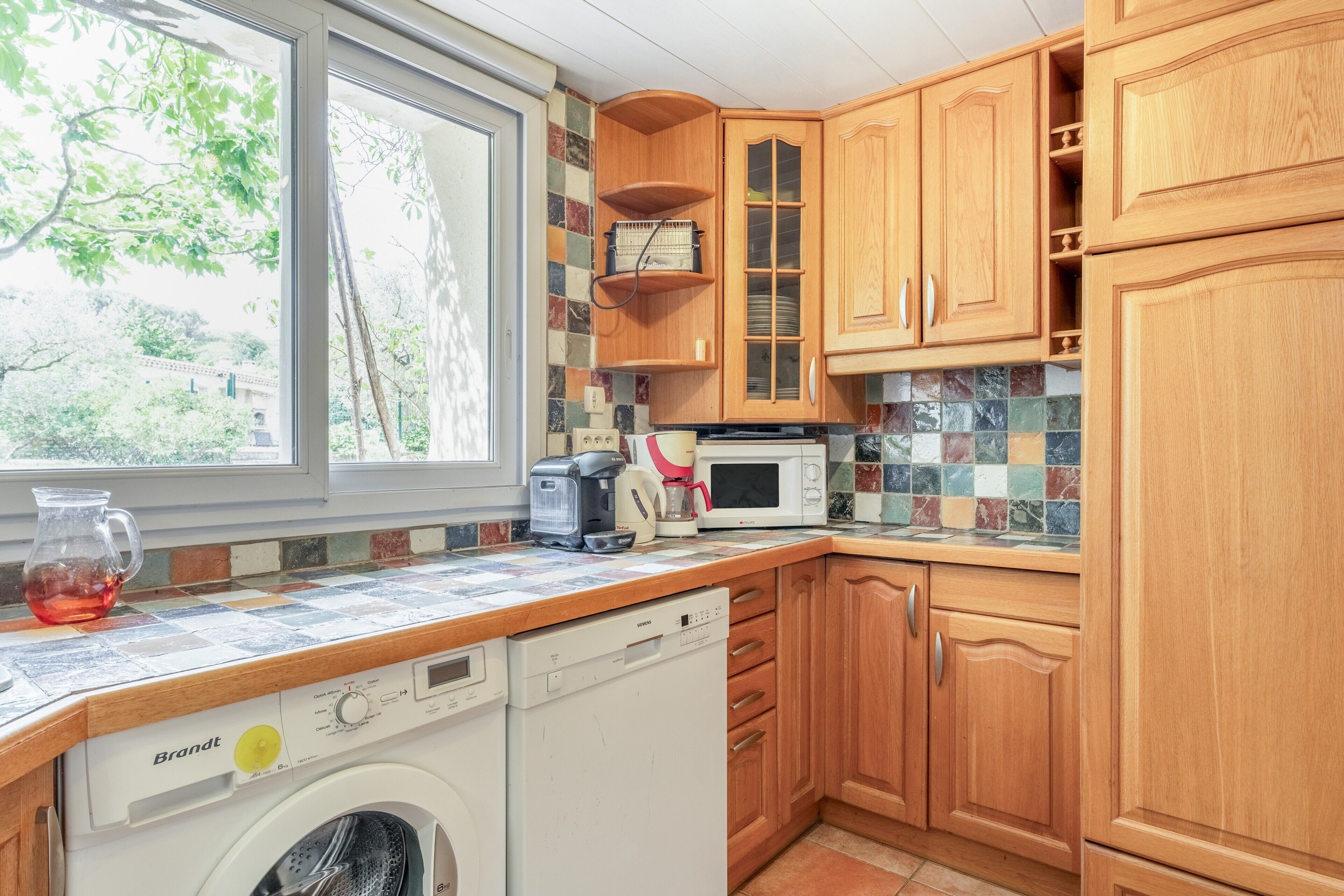 A kitchen with wooden cabinets, a dishwasher, a microwave, and a coffee maker.