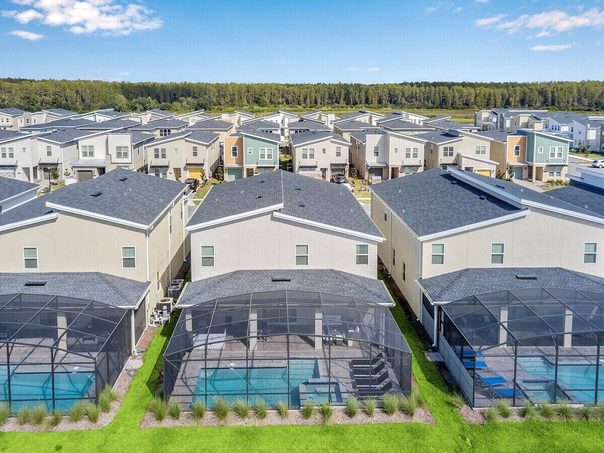 Un quartier résidentiel composé de plusieurs maisons à deux étages, chacune dotée d’une piscine extérieure couverte et d’un petit jardin.