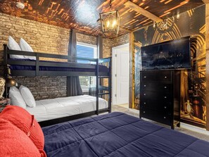 Een kamer met een stapelbed, een flatscreen televisie, een dressoir en een bakstenen muur.