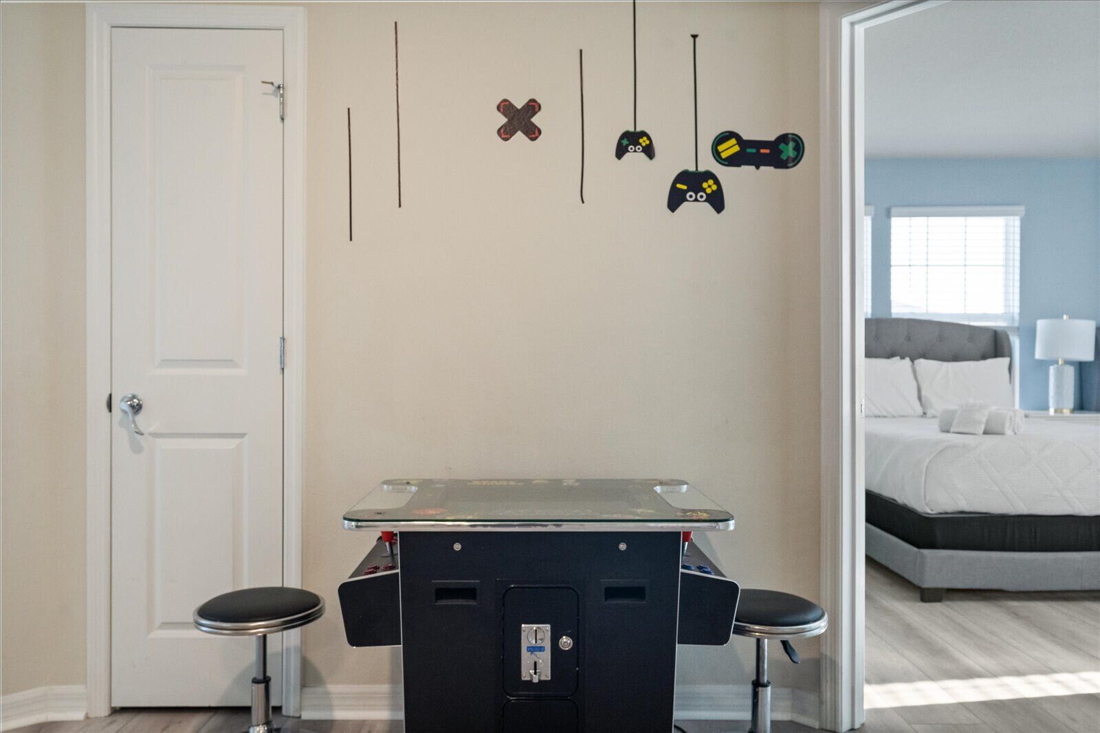Een kamer met een bed, een bureau met twee stoelen en wandgemonteerde game controllers.