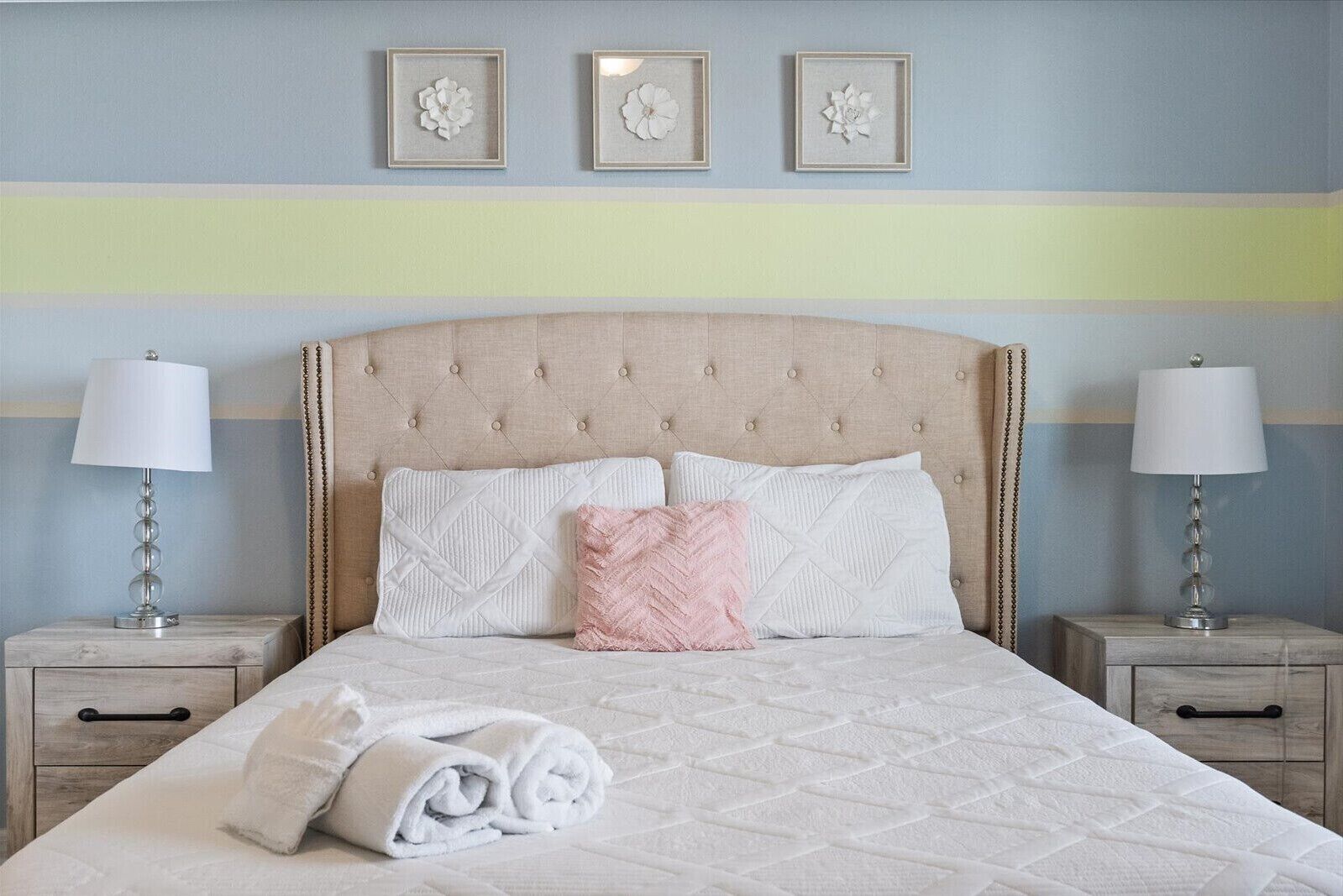 A neatly made bed with a quilted cover, two bedside lamps, and a headboard with a tufted design.
