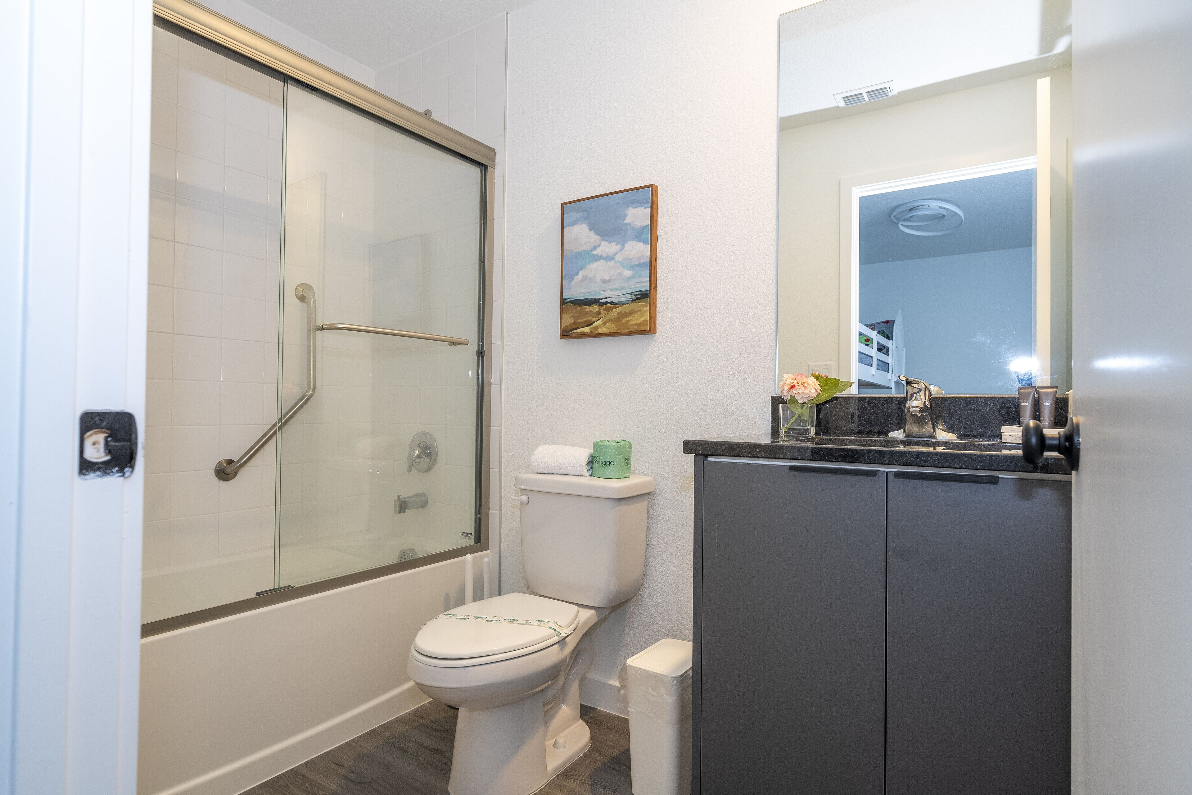 Une salle de bain avec une douche à parois de verre, des toilettes et un lavabo avec un miroir au-dessus.