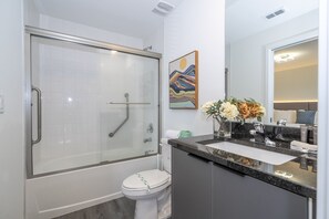 A modern bathroom with a glass-enclosed shower, a toilet, a sink with a marble countertop, and a mirror above the sink. - Last Minute Disney Getaway! Luxury Townhouse. Book Now! #125165 (Orlando)
