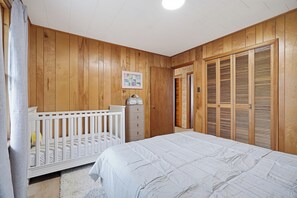 Une chambre à coucher avec un berceau, une commode, un lit et une armoire.