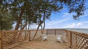 A wooden deck with a lattice railing, overlooking a body of water. - Private Lake Simcoe Retreat | Sandy Beach, Sunsets, Kayaks & Ice Fishing (Beaverton)