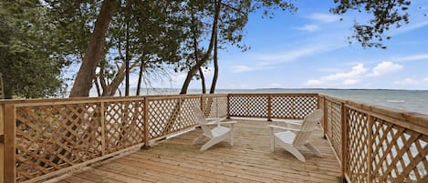 A wooden deck with a lattice railing, overlooking a body of water.