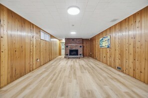 A spacious room with wooden paneling and a fireplace. - Private Lake Simcoe Retreat | Sandy Beach, Sunsets, Kayaks & Ice Fishing (Beaverton)