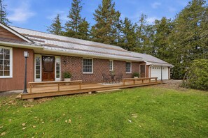Une maison de plain-pied en briques, dotée d’un porche à l’avant, d’un garage et d’un petit abri de jardin séparé.