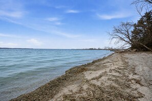 Une plage à l’eau claire, au rivage sablonneux et à la végétation clairsemée.