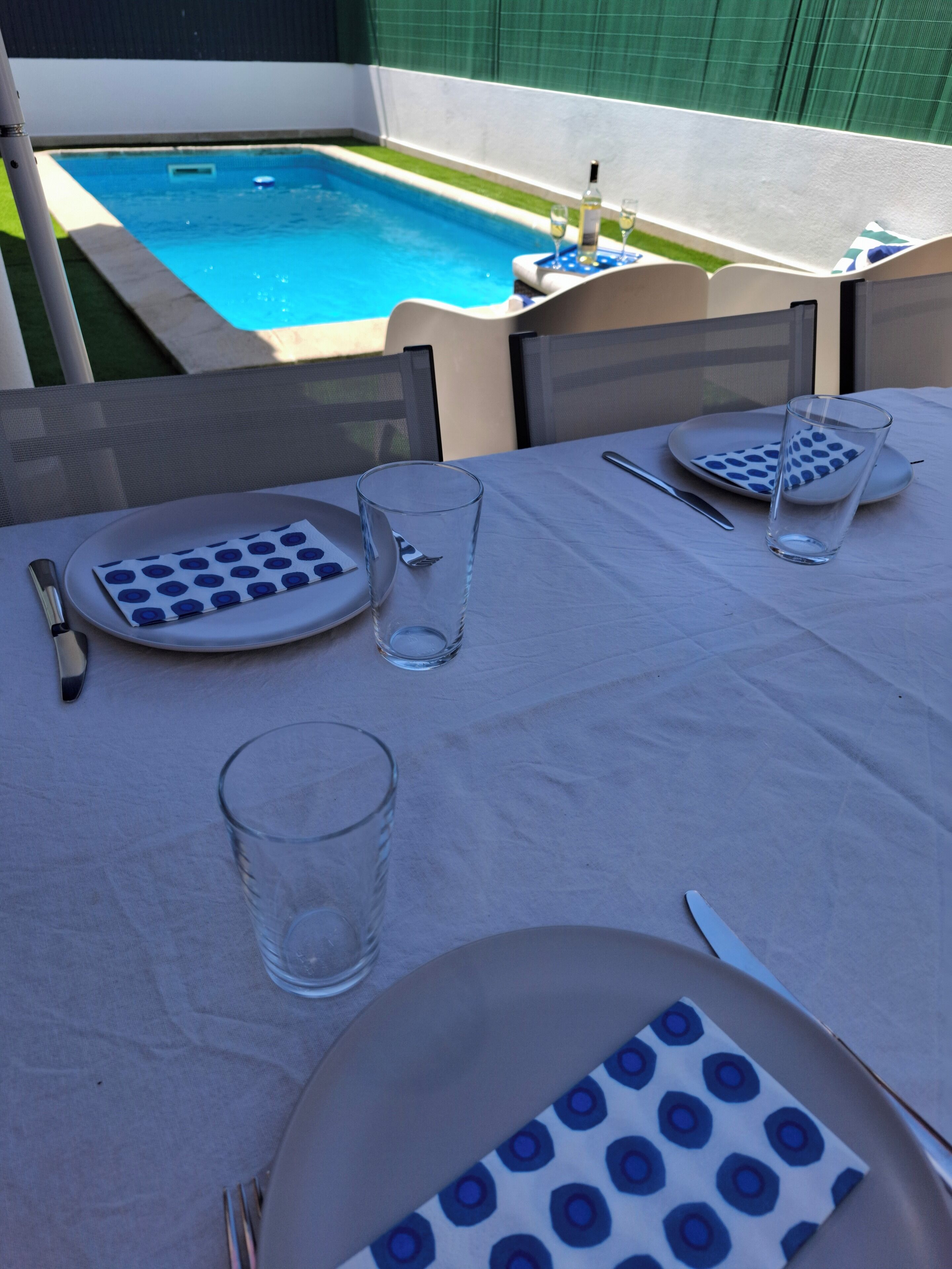 Una mesa de comedor dispuesta para dos personas, con platos, vasos, cubiertos y servilleta.