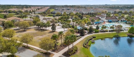 A residential area with a swimming pool, houses, and a large body of water.