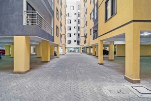 A multi-level parking garage with yellow pillars and a brick floor. - Zuri Premium Nyali, Furnished 1 Bedroom (Mombasa)