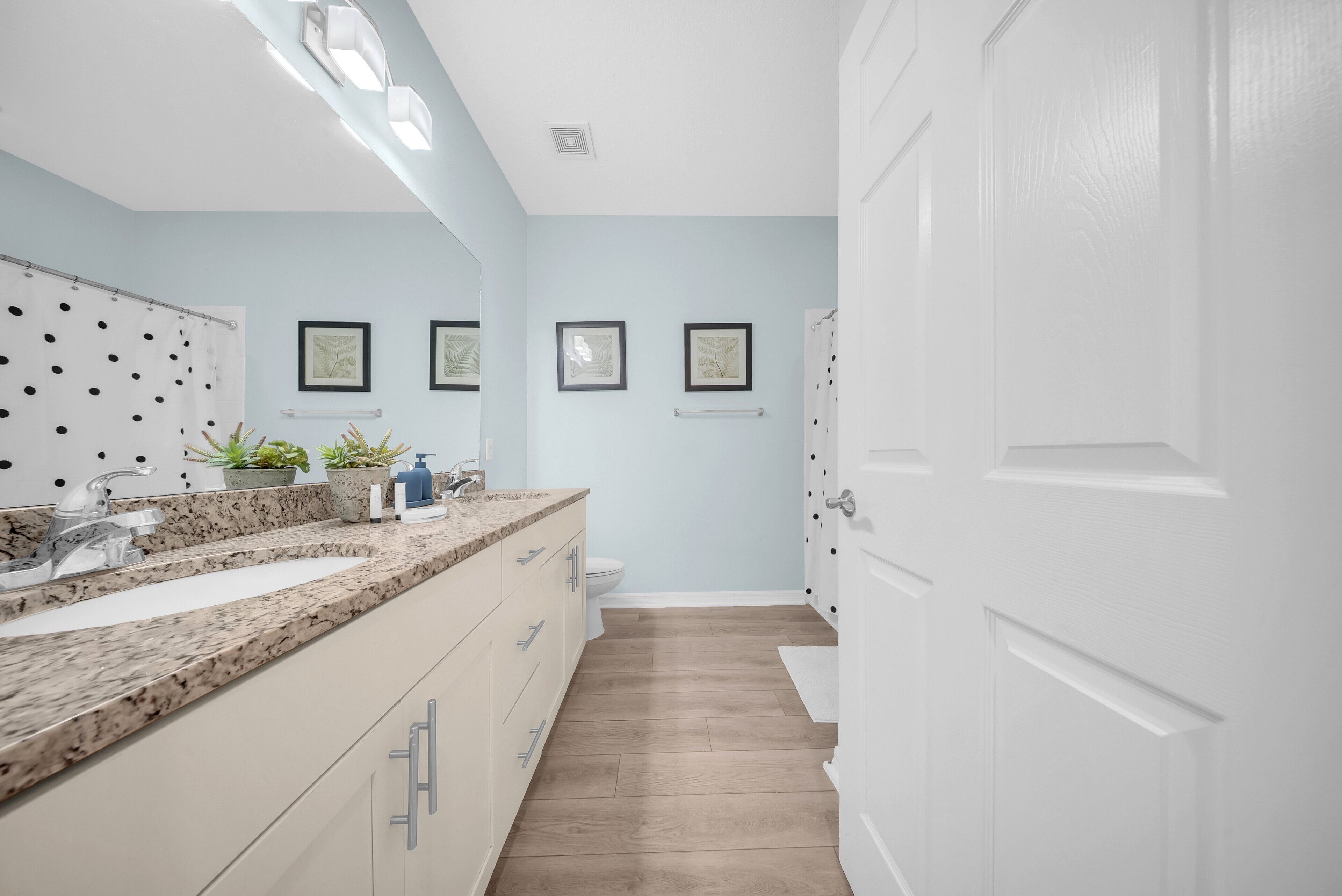 A modern bathroom with a double sink vanity, a toilet, and a shower area.