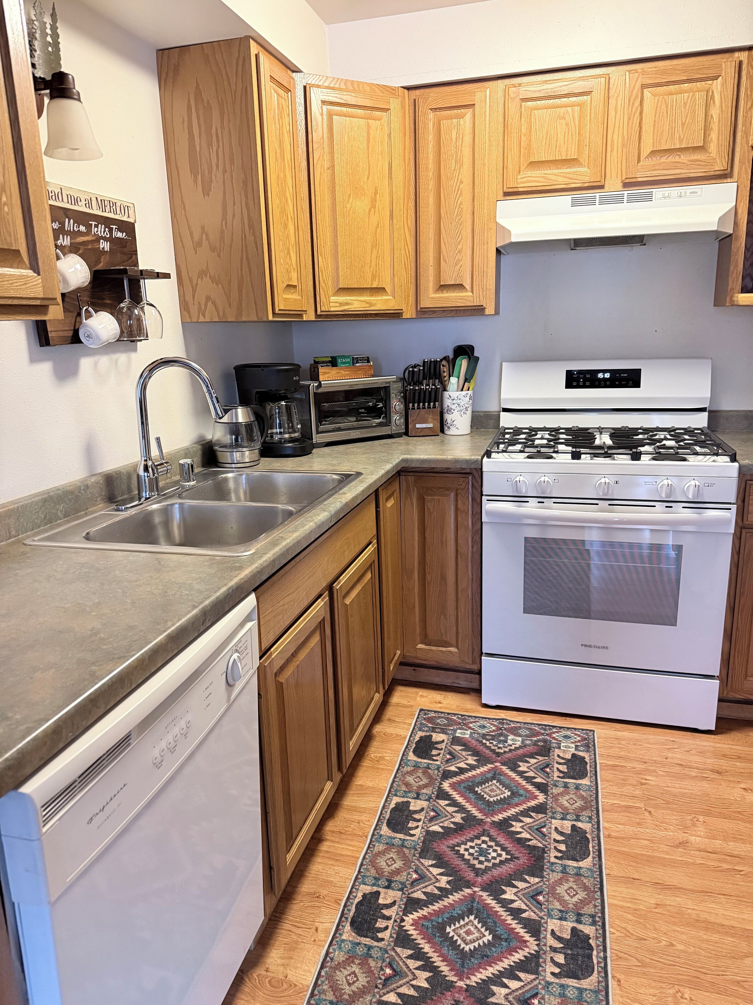 A kitchen with wooden cabinets, a stainless steel dishwasher, a white stove, and a coffee maker.
