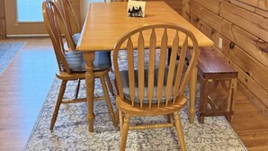 A wooden interior with a dining table, chairs, and a bench.