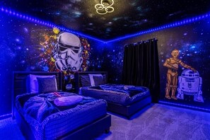 Een kamer met twee bedden, een muurschildering met Star Wars-thema en LED-verlichting.