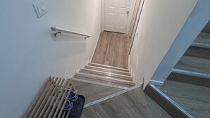 Een smalle trap met een leuning, een deur aan de bovenkant en een houten vloer.