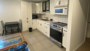 Een moderne keuken met witte kasten, een roestvrijstalen oven en een magnetron.