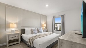 A modern bedroom with a large bed, bedside tables with lamps, a TV, and a window with curtains. - Last Minute Disney Getaway! Modern Townhome. Book Now! #158993 (Orlando)
